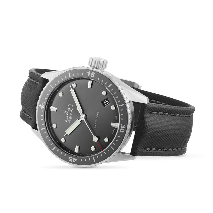 The Blancpain Fifty Fathoms Bathyscaphe is a black diver’s watch with a black rotating bezel, black dial, luminous markers, date at 3 o’clock, and a textured strap, powered by the reliable 1315 calibre automatic movement.