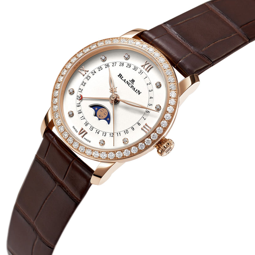 A Blancpain Villeret Quantième Phases de Lune wristwatch features a brown leather strap, 18K red gold case, diamond bezel, Roman numerals, date indicators, and a moon phase display on the silver dial.
