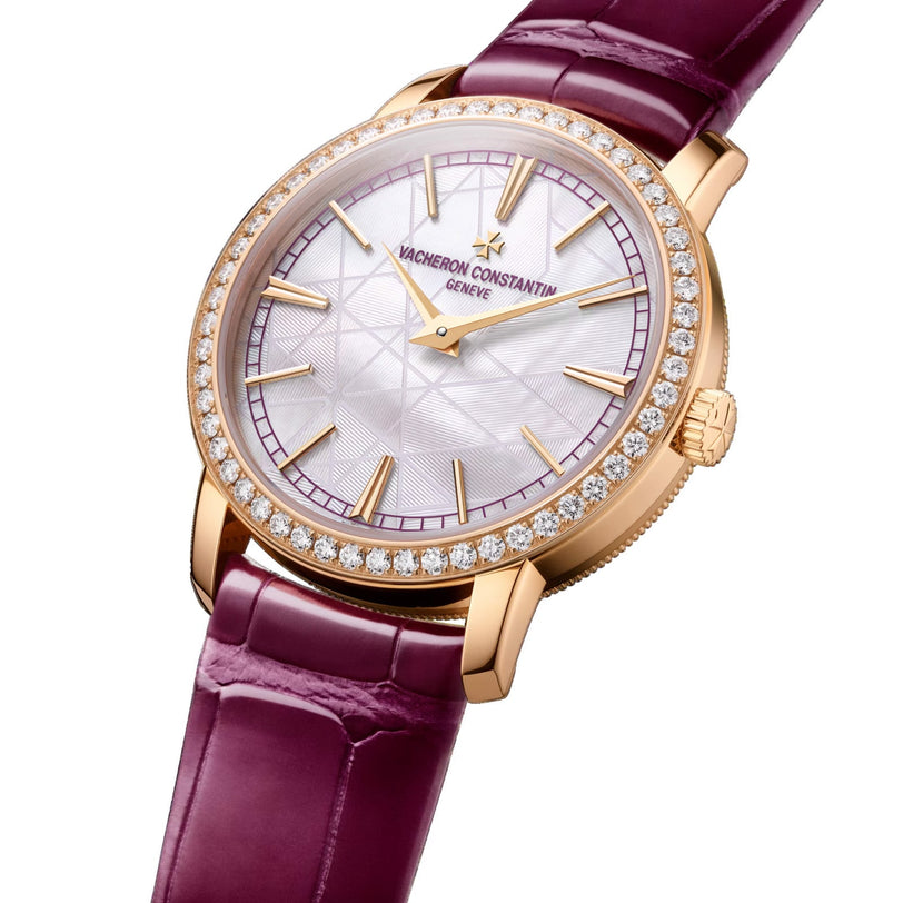 The Vacheron Constantin Traditionnelle Manual-winding is a limited edition wristwatch with a diamond bezel, 18K pink gold case, textured white dial, gold hour markers, and a burgundy leather strap.