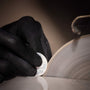 A gloved hand holds a round, translucent object to a spinning grinder—a precise process akin to crafting the Vacheron Constantin Traditionnelle Manual-winding timepiece.