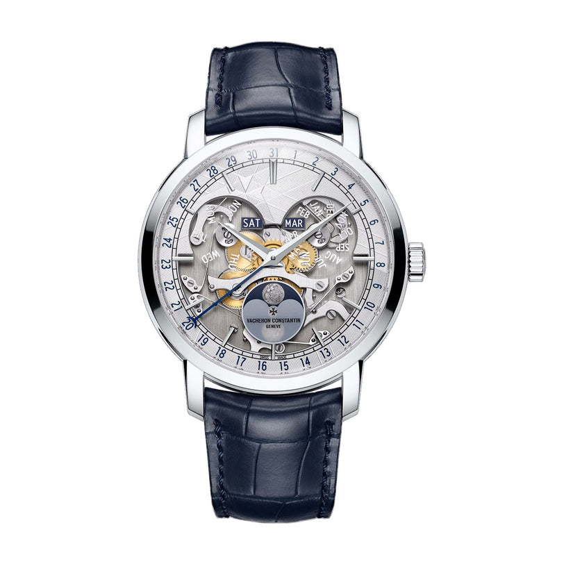 The Vacheron Constantin Traditionnelle Complete Calendar Openface is a luxury platinum watch with a skeleton dial, blue leather strap, and silver case, featuring day, date, month, and moon phase indicators.