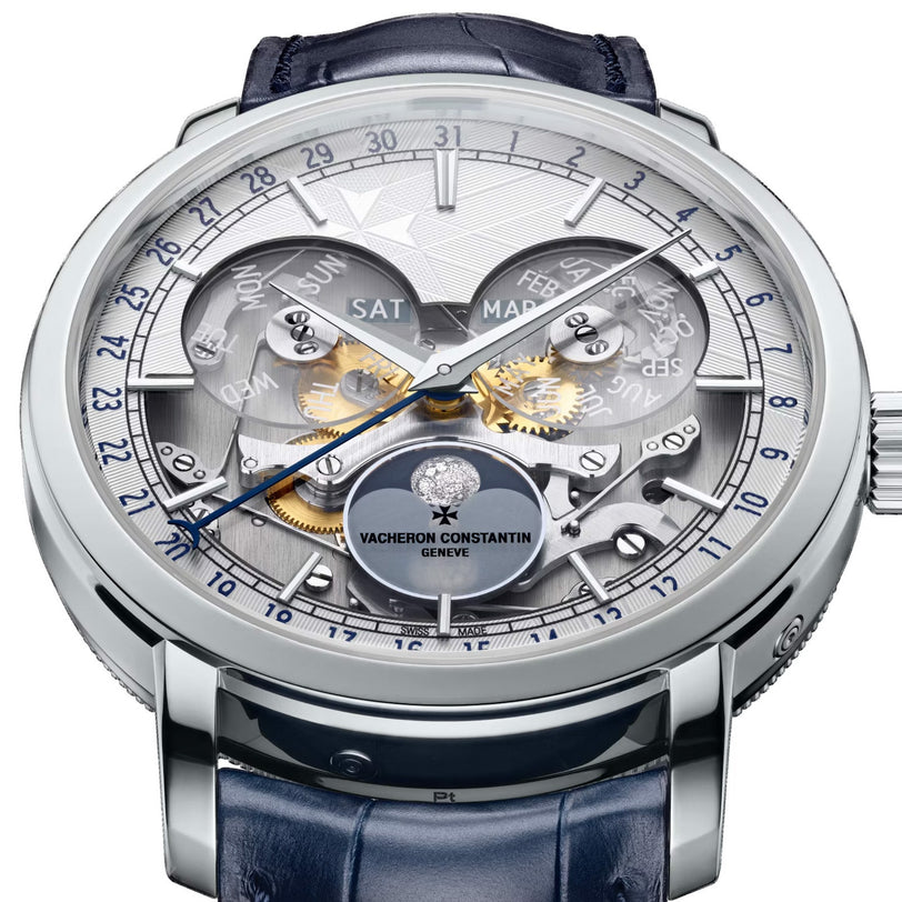 Close-up of a Vacheron Constantin Traditionnelle Complete Calendar Openface platinum watch with exposed gears, multi-dial full calendar display (day, date, month, time), and a blue leather strap.