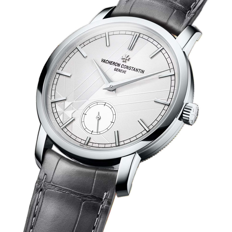 A limited edition Vacheron Constantin Traditionnelle Manual-Winding watch with a white dial, silver hour markers, and a grey leather strap, viewed at an angle.