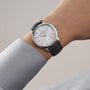 A person wearing a limited edition Vacheron Constantin Traditionnelle Manual-Winding platinum watch with a black leather strap and small seconds subdial on their left wrist.