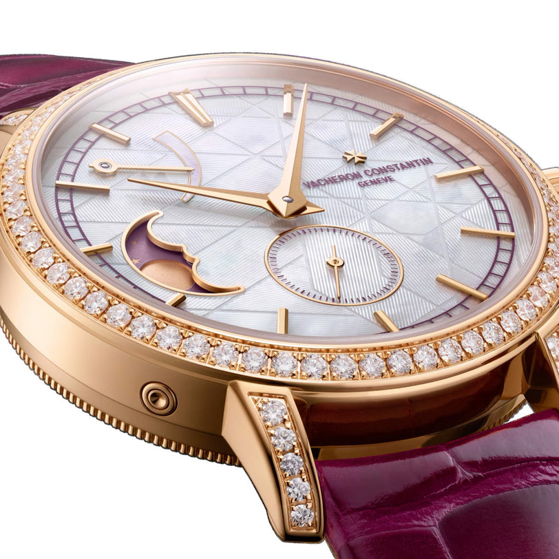 Close-up of the Traditionnelle Moon Phase by Vacheron Constantin, a pink gold watch with a diamond bezel, purple leather strap, gold hands, and an elegant moon phase subdial on its detailed dial.