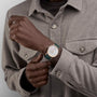 A person in a light grey button-up shirt showcases the Vacheron Constantin Patrimony Self-Winding, a limited edition gold watch with a green strap and Geneva Seal, on their left wrist.