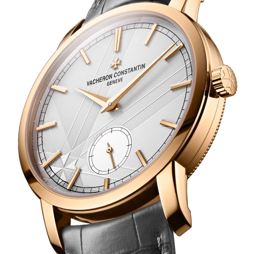 The Vacheron Constantin Traditionnelle Manual-winding is a limited edition 18K pink gold wristwatch with a silver geometric-patterned dial, gold hour markers, and a black leather strap.