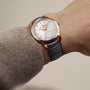 A person wearing a Vacheron Constantin Traditionnelle Manual-winding watch with a white dial, 18K pink gold accents, and a black leather strap.