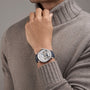 A person in a taupe ribbed turtleneck sweater showcases a Vacheron Constantin Traditionnelle Perpetual Calendar Retrograde Date Openface platinum watch with visible self-winding movement and a dark strap on their left wrist.