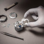 A gloved hand assembles a Vacheron Constantin Traditionnelle Perpetual Calendar Retrograde Date Openface movement on a work surface, surrounded by watch parts, a screwdriver, and tweezers.
