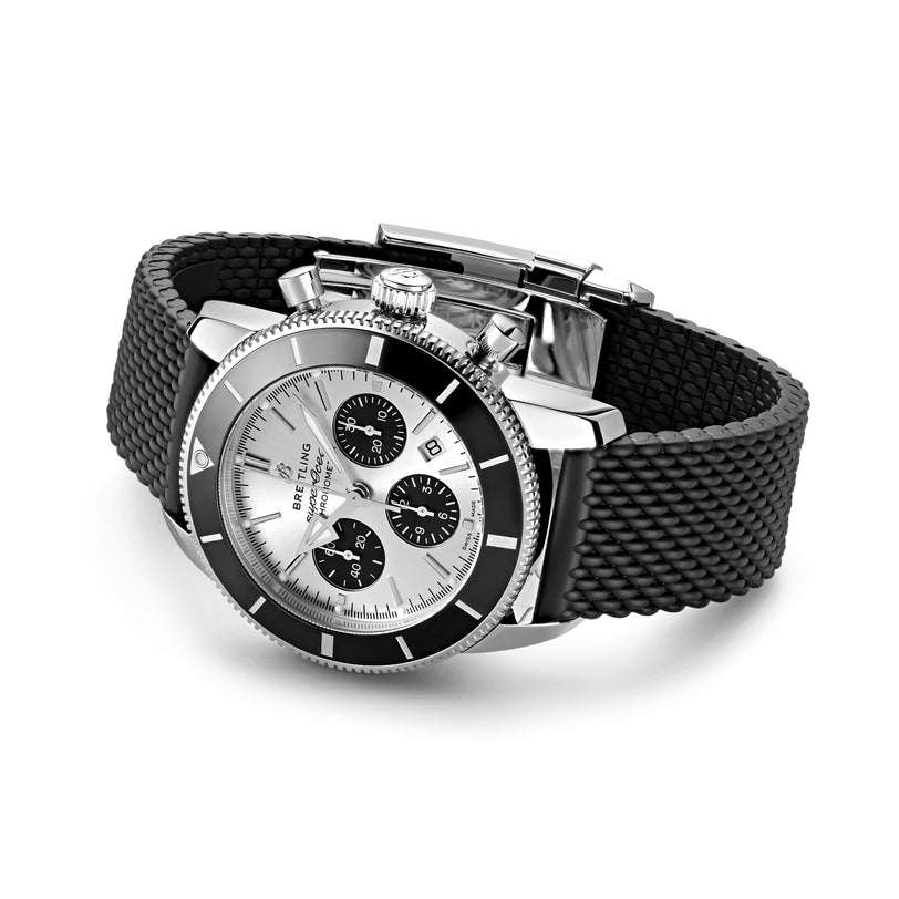 A Breitling Superocean Heritage B01 Chronograph 44 wristwatch in silver and black, with a mesh-patterned black rubber strap, is displayed on a white background.