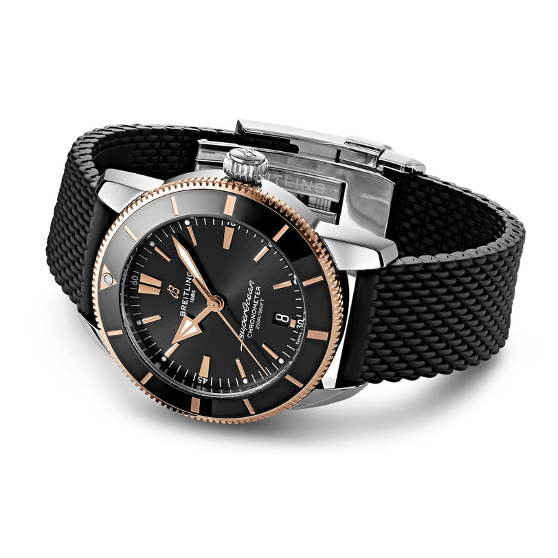 The Breitling Superocean Heritage B20 Automatic 44 wristwatch, in black and gold with a black textured strap, is displayed at an angle on a white background.