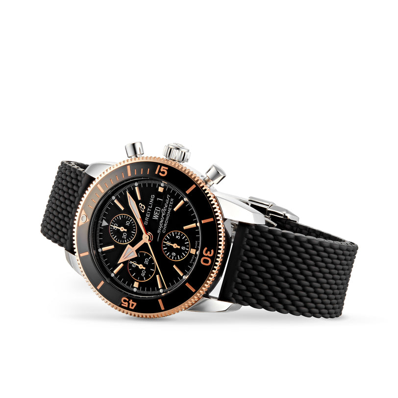 The Breitling Superocean Heritage B20 Automatic 44 is a luxury black chronograph watch featuring a textured strap and rose gold accents, displayed on a white background.