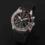 A Breitling Superocean Heritage B20 Automatic 44 in black and rose gold, featuring a high-tech ceramic bezel and black textured strap, is showcased on a dark surface.