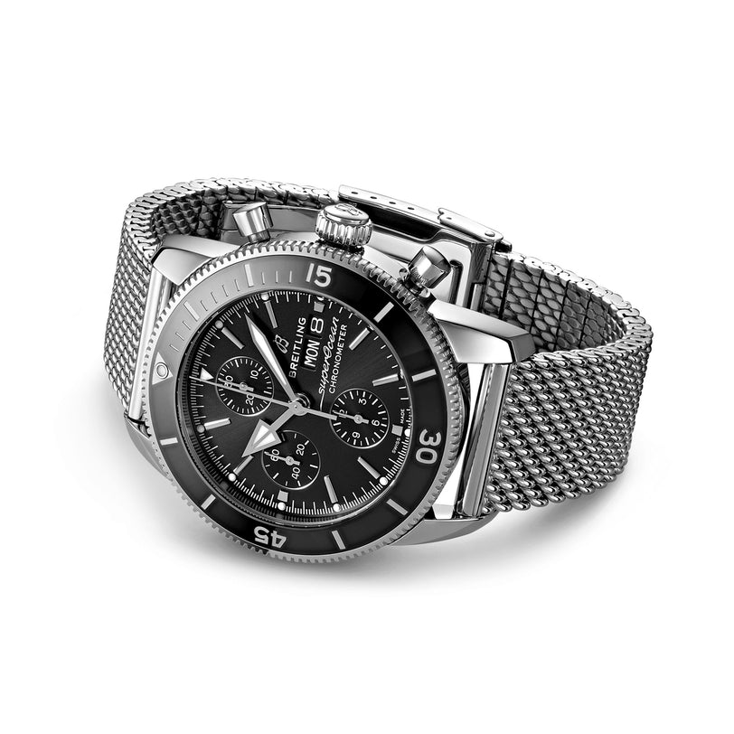 The Breitling Superocean Heritage Chronograph 44 is a stainless steel wristwatch with a black dial, three subdials, date display, mesh metal bracelet, and Breitling 13 calibre movement, shown on a white background.