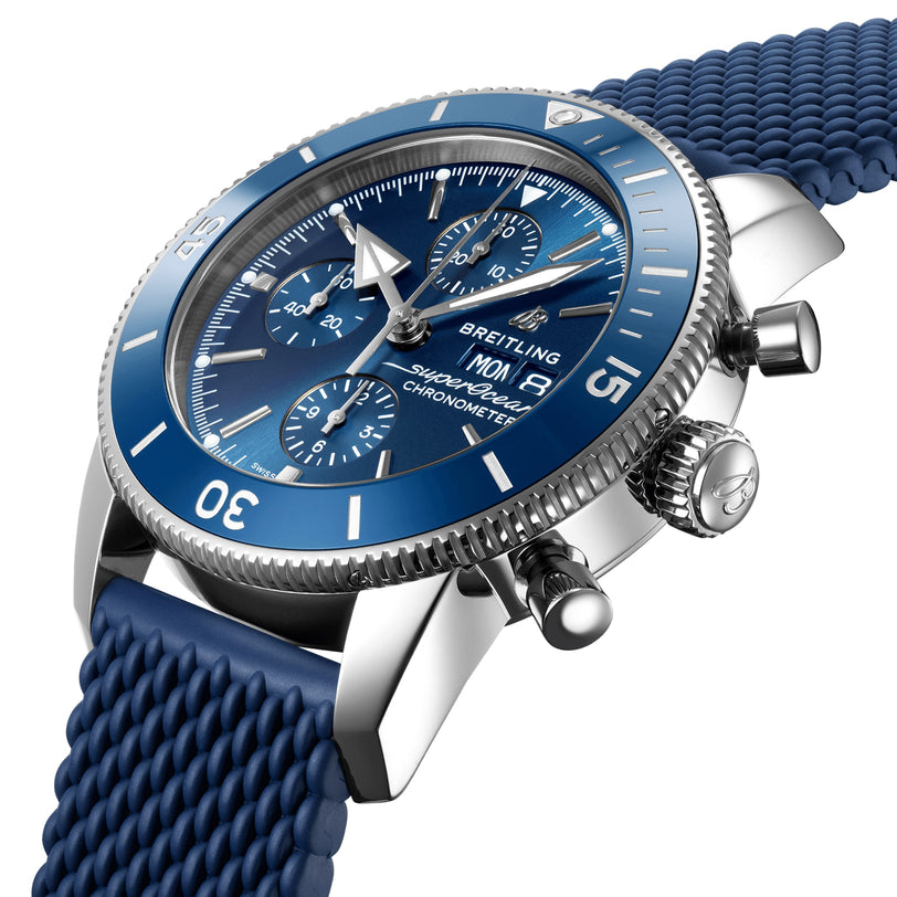 A close-up of the Breitling Superocean Heritage Chronograph 44 reveals its blue dial with three subdials and a blue textured strap, powered by the precise Breitling 13 calibre.