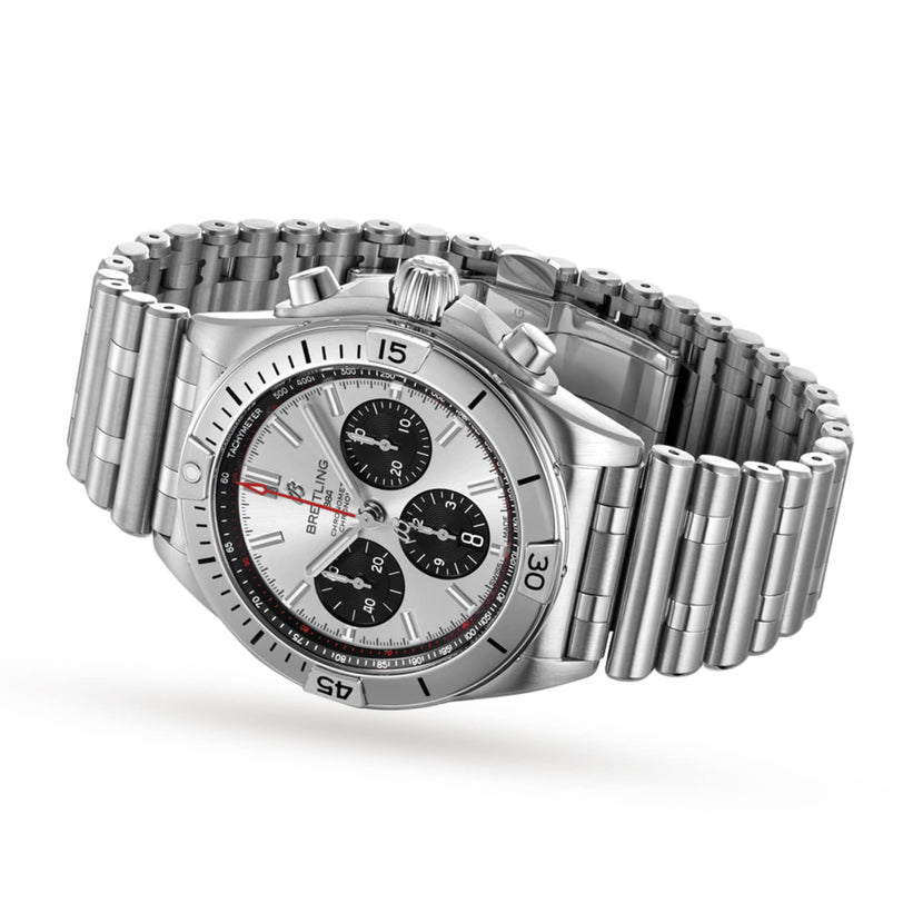 The Breitling Chronomat B01 42, a stainless steel timepiece featuring a silver dial with three black subdials and a signature Rouleaux bracelet, is displayed at an angle.
