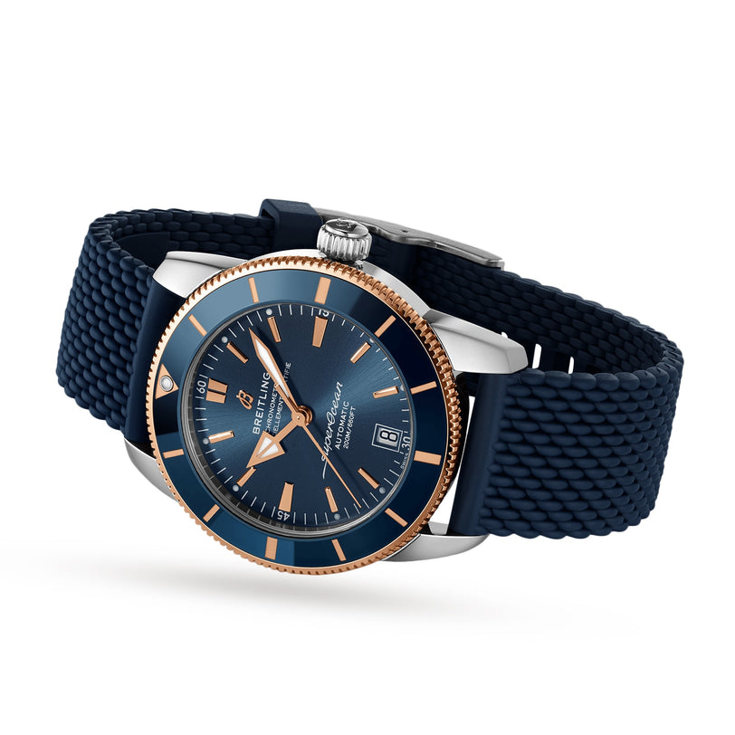 The Breitling Superocean Heritage B20 Automatic 42 features a blue dial, blue textured strap, date display, and an 18K red gold case, all shown against a white background.