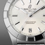 Close-up of a Breitling Chronomat 32 watch featuring a white dial, silver hour markers, date window at 6 o’clock, and stainless steel case and bracelet; COSC-certified chronometer.