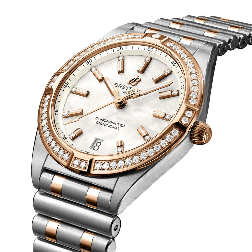 The Breitling Chronomat 32 features a silver and gold metal band, diamond-set bezel, white dial, gold hour markers, and a date window at 6 o’clock.