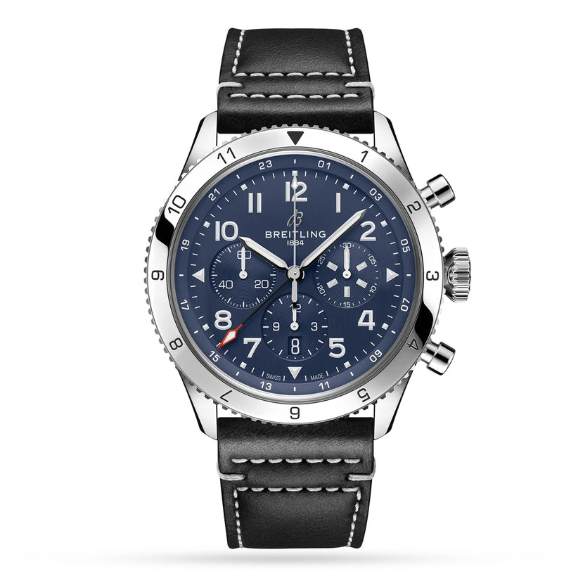The Breitling Super AVI B04 Chronograph GMT 46 Tribute To Vought F4U is a stainless steel watch with a blue dial, three subdials, white numerals, and a black leather strap with white stitching.