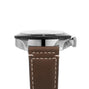 Side view of the Breitling Super AVI B04 Chronograph GMT 46 Mosquito, inspired by aviation history and featuring a silver bezel, black dial, and brown leather strap with white stitching.