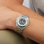 A person wearing a Breitling Superocean Automatic 44 dive watch with a stainless steel case, dark face, silver bezel, and metal link band rests their arm on a light-colored surface.
