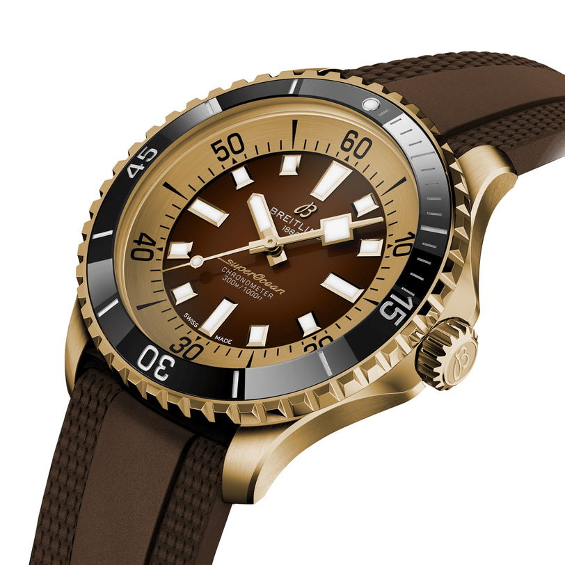 The Breitling Superocean Automatic 44 dive watch features a brown dial, bronze case, black bezel, and a brown textured rubber strap, displayed at an angle.