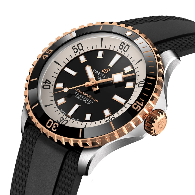 The Breitling Superocean Automatic 42 features a black dial, gold bezel, and black rubber strap—its design echoing the iconic 1960s Slow Motion era, shown at an angle to highlight the face and crown details.