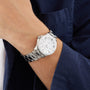 A person wears the Breitling Superocean Automatic 36, featuring a stainless steel case and white dial, paired with a navy blue jacket over a white shirt—embodying classic dive watch style.