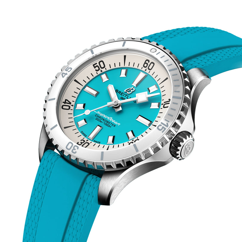 The Breitling Superocean Automatic 36 is a silver diving watch with a turquoise dial, matching rubber strap, large white hour markers, and a ceramic-inlaid unidirectional bezel.