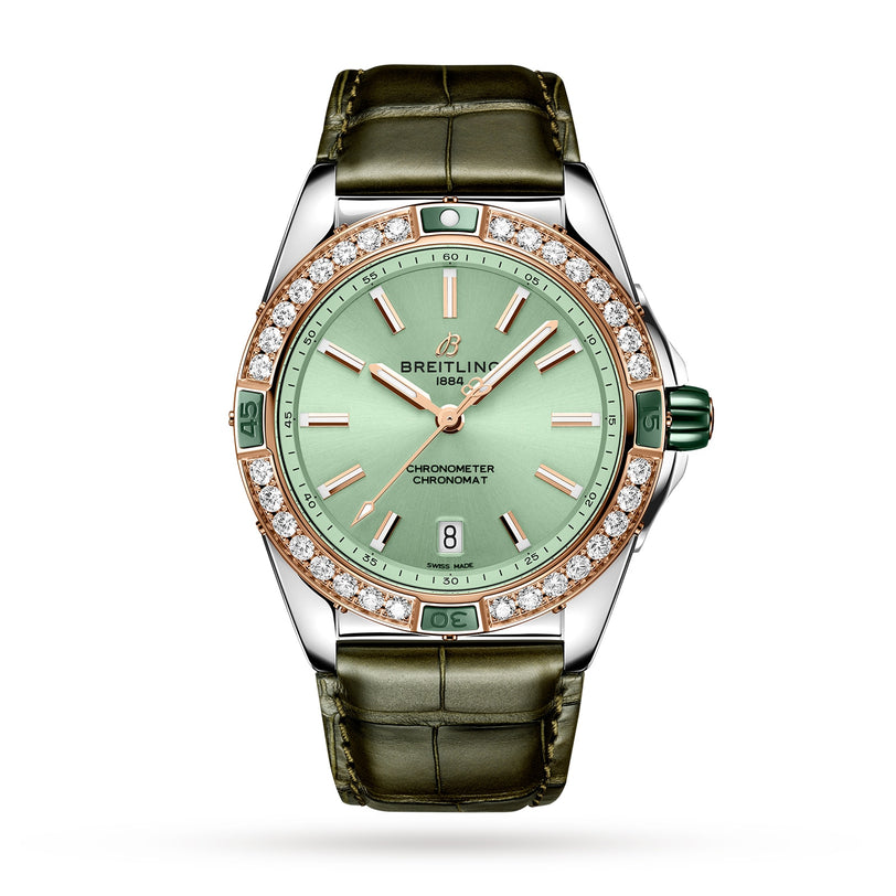 The Breitling Super Chronomat Automatic 38 features a green leather strap, green dial, gold hour markers, diamond bezel, date at 6 o’clock, and runs on the Breitling 17 calibre movement, shown against a white background.