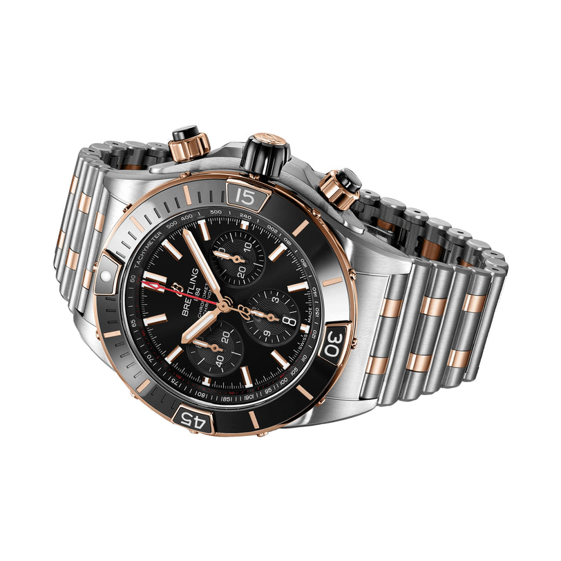 The Breitling Super Chronomat B01 44, a luxury stainless steel and 18ct rose gold wristwatch with a black dial and three subdials, is elegantly displayed at an angle on a white background.