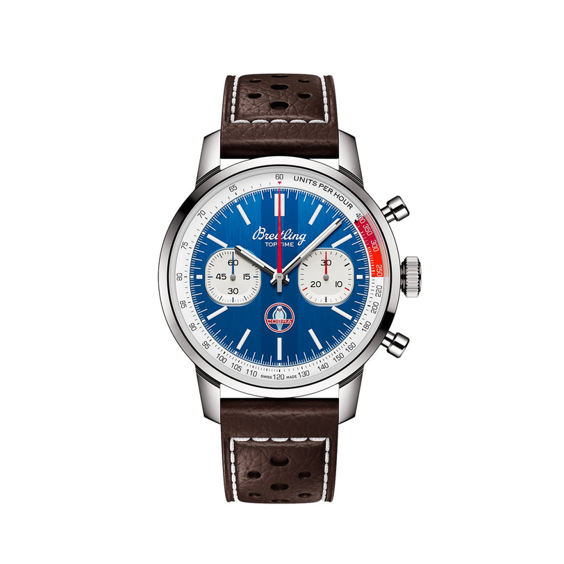 The Breitling Top Time B01 Shelby Cobra is a chronograph wristwatch with a blue dial, white subdials, tachymeter markings, silver case, and a brown perforated leather strap with white stitching.