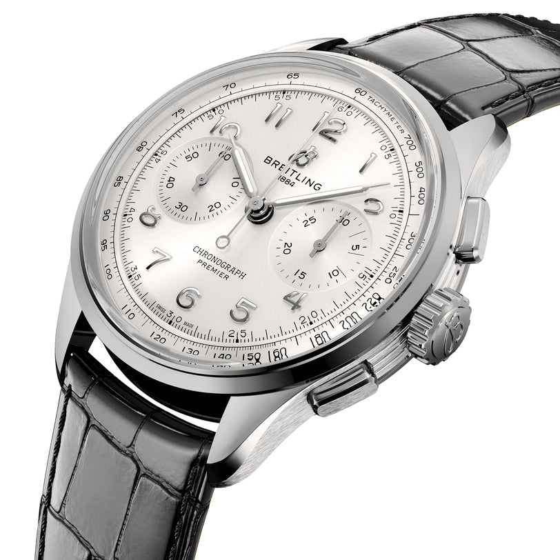 The Breitling Premier B09 Chronograph 42 features a stainless steel case, white dial with three subdials, and black leather strap. Shown at an angle on a white background.