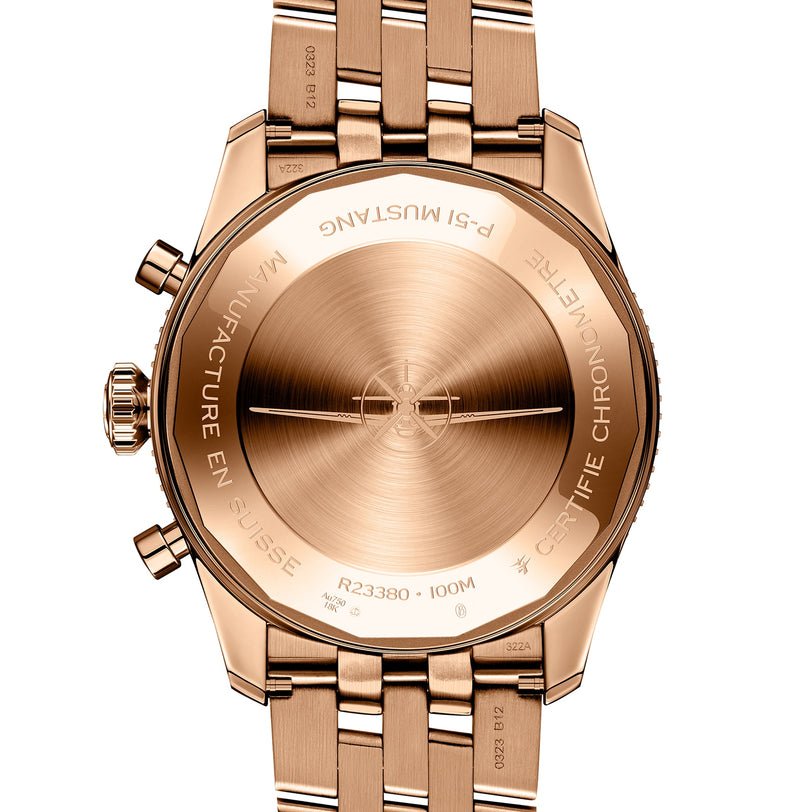 Close-up of the back of a gold Breitling Classic AVI Chronograph 42 P-51 Mustang, showing engraved text such as P.S. MUSTANG, MANUFACTURE EN SUISSE, CERTIFIE CHRONOMETRE, and 100M—a true pilot’s watch.