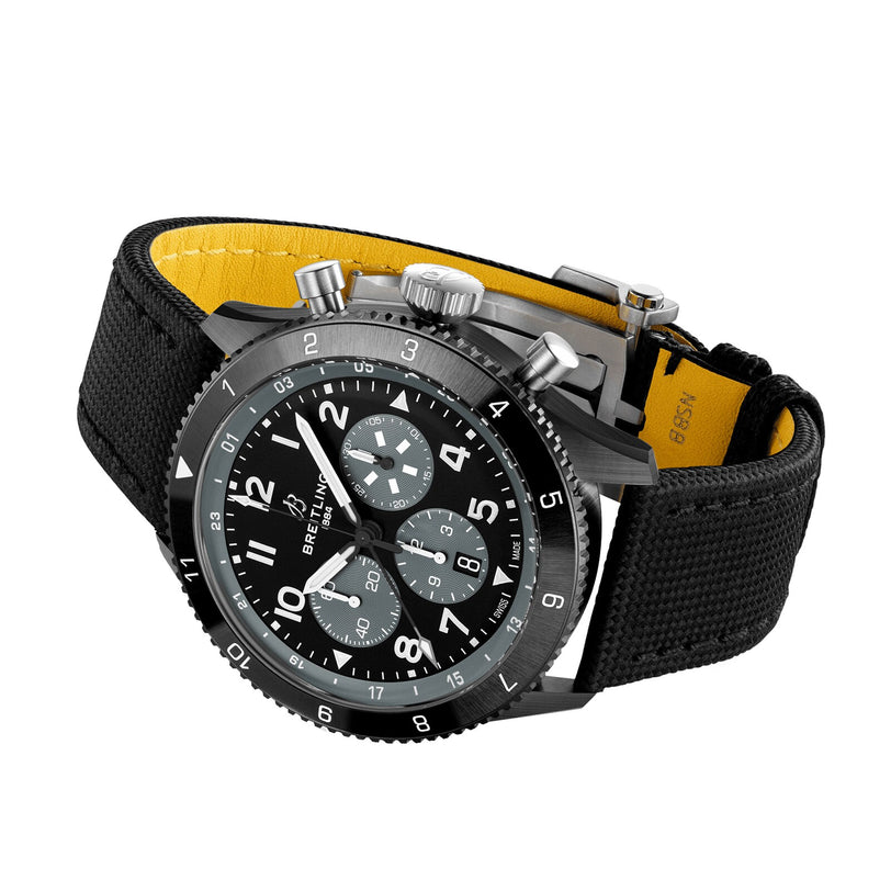 The Breitling Super AVI B04 Chronograph GMT Mosquito Night features a black dial with white numerals, three sub-dials, fabric strap, and yellow lining—honoring aviation history and the legendary de Havilland Mosquito.