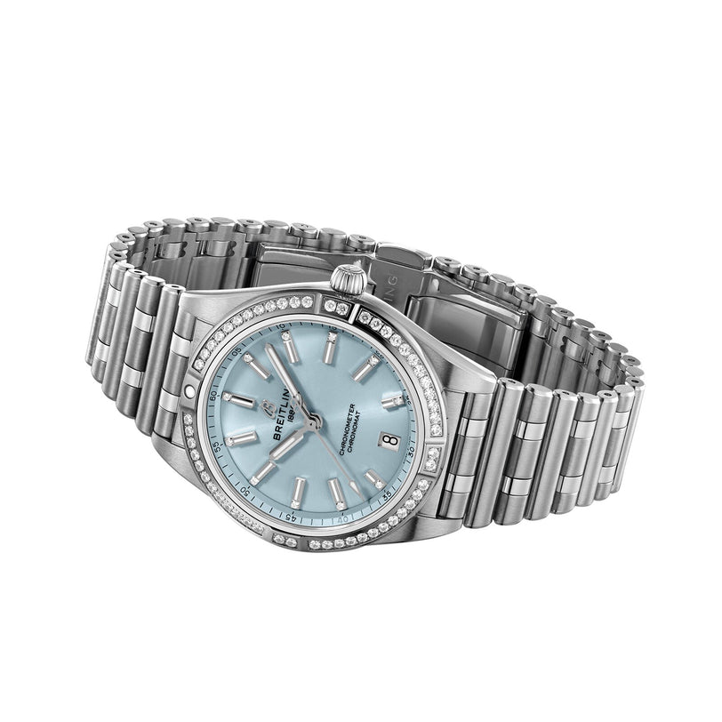 The Breitling Chronomat Automatic 36 is a silver wristwatch with an ice blue dial, diamond-set hour markers and bezel, date display, and shown at an angle on a metal link bracelet.