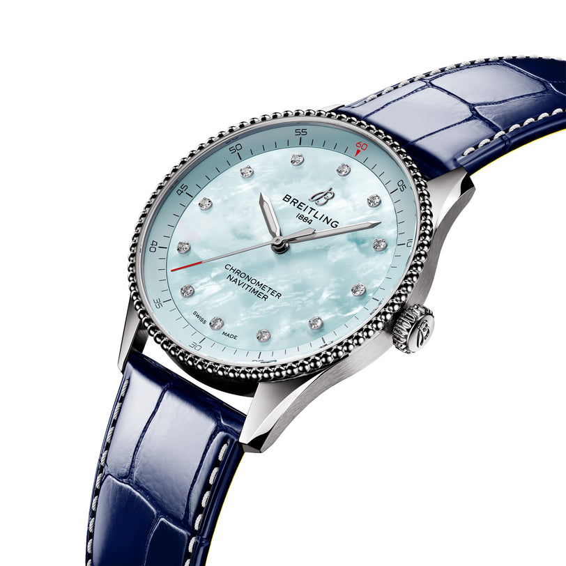 The Breitling Navitimer 32 features a blue mother-of-pearl dial, diamond hour markers, and a blue leather strap, elegantly displayed on a white background.