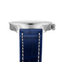 Side view of the Breitling Navitimer 32 watch case in silver, featuring a textured bezel, blue leather strap with white stitching, right-side crown, and diamond hour markers on a blue mother-of-pearl dial.