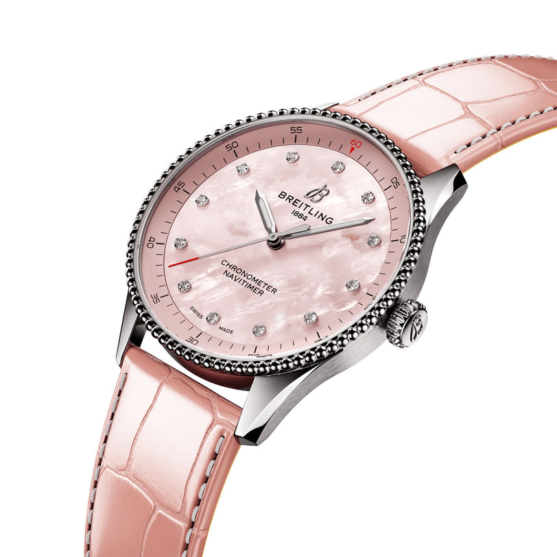 The Breitling Navitimer 32 features a pink mother-of-pearl dial with diamond hour markers and a pink leather strap, powered by the Breitling 77 calibre, elegantly displayed at an angle.