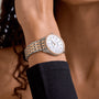Someone wearing a Breitling Navitimer 32 with a white dial, diamond hour markers, and 18K red gold accents, dressed in a black sleeve.