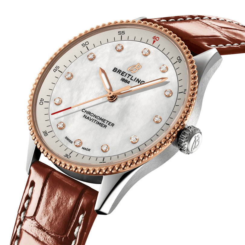 The Breitling Navitimer 32 wristwatch features a brown leather strap, white dial, rose gold bezel, diamond hour markers, and gold hands, shown at an angle.