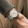 A close-up of a person wearing a Breitling Navitimer Automatic 36 with a silver case, white dial, and metal link band on their left wrist.