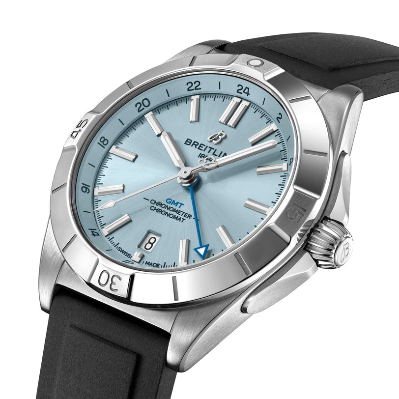 The Breitling Chronomat Automatic GMT 40 sports watch features a stainless steel case, light blue dial, dual time zone functionality, and a black rubber strap, shown at a slight angle.