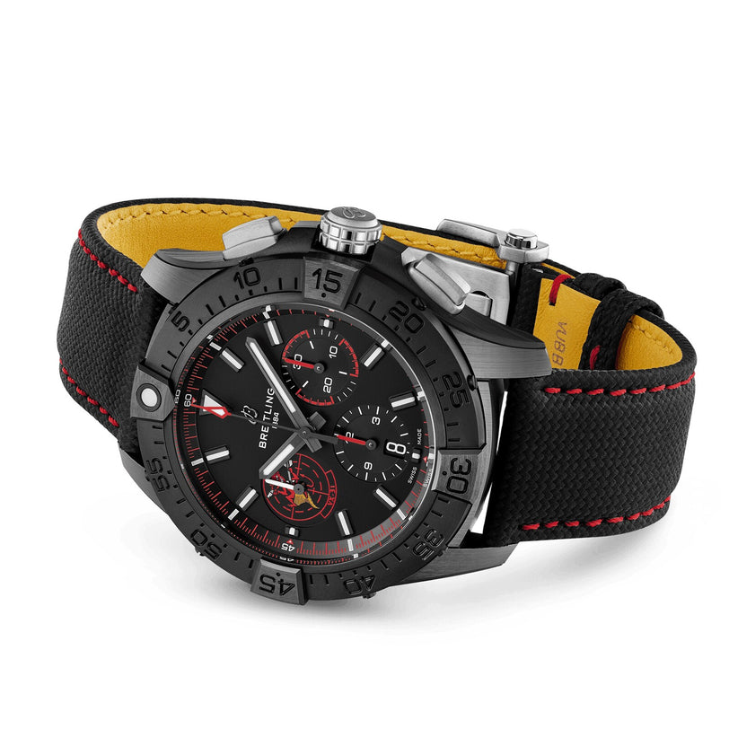 The Breitling Avenger B01 Chronograph 44 Night Mission Dust Devils features a black dial with red accents, three subdials, and a black fabric strap with red stitching and yellow lining. Powered by the Breitling Manufacture Caliber 01.