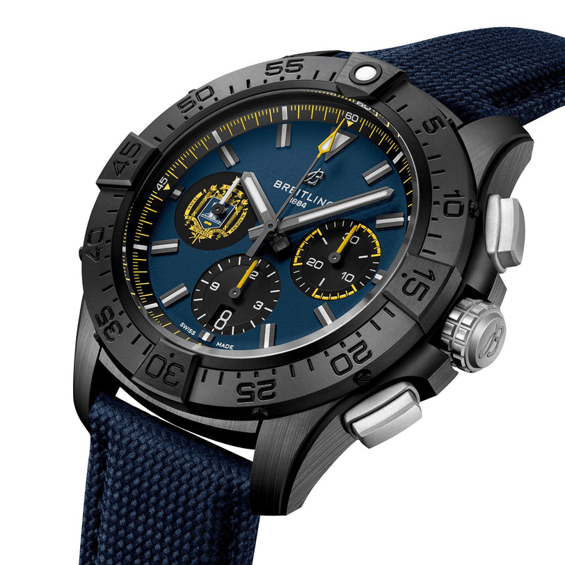 The Breitling Avenger B01 Chronograph 44 Night Mission US Naval Academy features a blue dial, black bezel, yellow accents, two subdials, date display, and a blue fabric strap, powered by the Manufacture Caliber 01.
