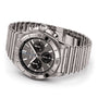 The Breitling Chronomat B01 42 is a chronograph watch with a black dial, three subdials, date display, and silver link bracelet, powered by the Breitling 01 calibre movement and displayed on a white background.