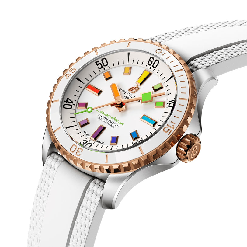 The Breitling Superocean Automatic 36 is a luxury 36mm stainless steel watch with a white strap, rose gold bezel, and white dial with multi-colored markers and hands, inspired by the iconic Superocean design.