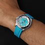 The Breitling Superocean Automatic 44 with a turquoise face and water resistant turquoise rubber strap is shown worn on a wrist against a black background.